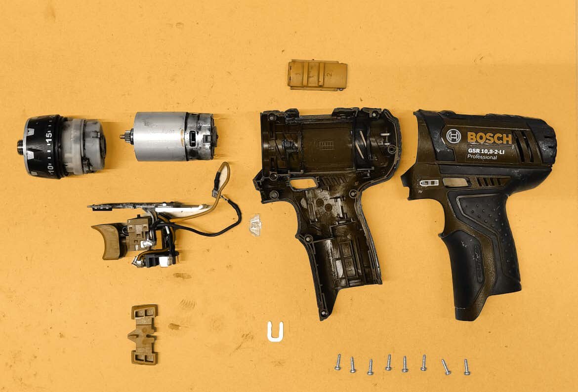 Three power drills disassembled into their components for design research